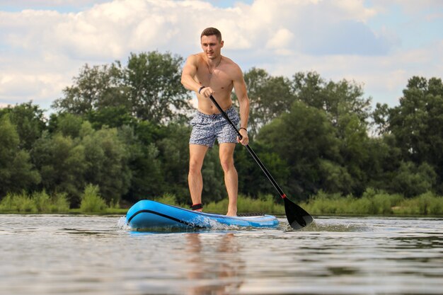 Jovem praticando paddleboard em um rio durante o dia