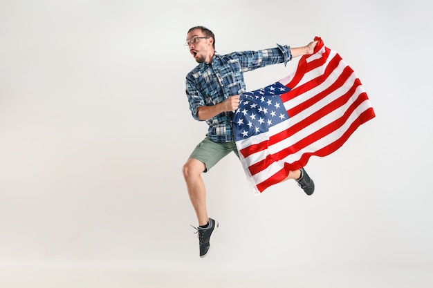 Jovem pulando com a bandeira dos Estados Unidos da América, isolado no estúdio branco.