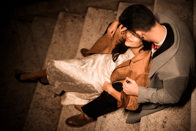 Foto grátis jovem rapaz abraçando e beijando elegante senhora sentada nos degraus