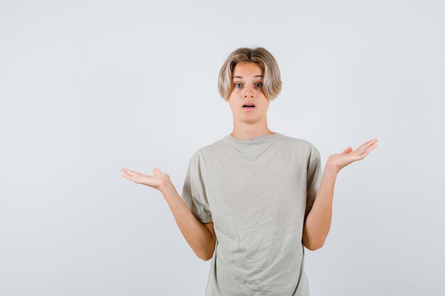 Jovem rapaz adolescente mostrando um gesto desamparado em t-shirt e parecendo perplexo. vista frontal.
