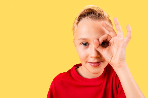 Jovem rapaz cobrindo os olhos com sinal ok