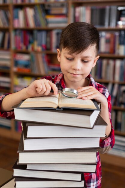 Jovem rapaz com pilha de livros de leitura