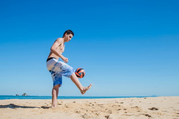 Jovem rapaz fazendo algum esporte na praia