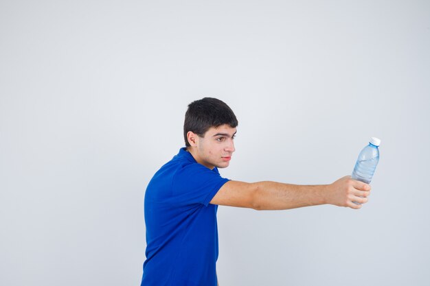 Jovem rapaz segurando a garrafa de água, dando a alguém de camiseta azul e parecendo feliz. vista frontal.