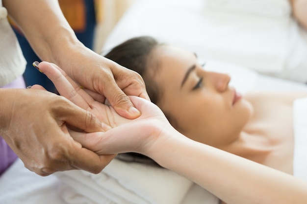 Jovem recebendo massagem nas mãos no spa.