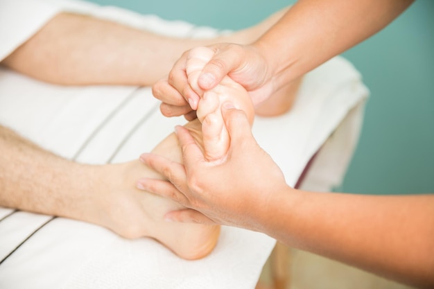 Jovem recebendo uma massagem nos pés de um terapeuta em um spa. Visto de perto
