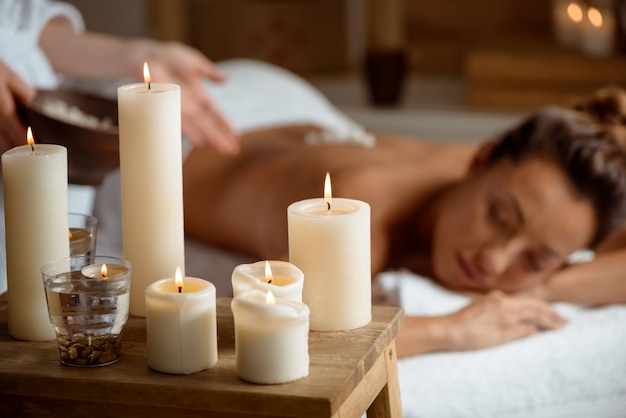 Jovem relaxante no salão spa. concentre-se em velas.