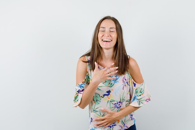 Jovem rindo alto em camiseta, jeans e parecendo feliz. vista frontal.