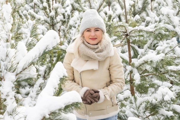 Jovem rindo feliz mulher caucasiana e ramos de pinheiro na floresta de inverno. emoções positivas, andando em clima de neve Foto Premium