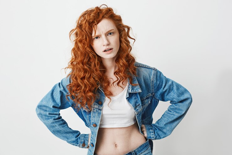Foto grátis jovem rude com cabelo encaracolado vermelho brutalmente com braços akimbo.