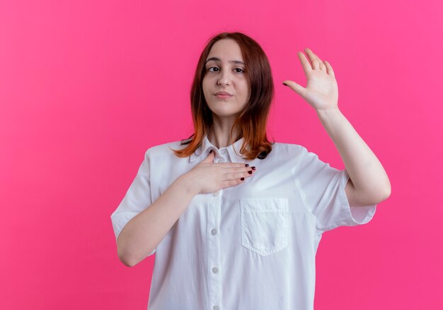 jovem ruiva colocando a mão no peito e mostrando um gesto de parada isolado na parede rosa