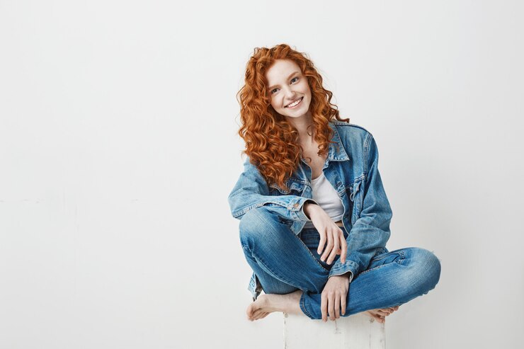 Foto grátis jovem ruiva linda sorrindo sentado na caixa. copie o espaço.