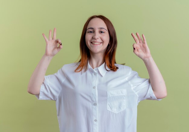 Jovem ruiva sorridente mostrando gesto certo isolado em verde oliva