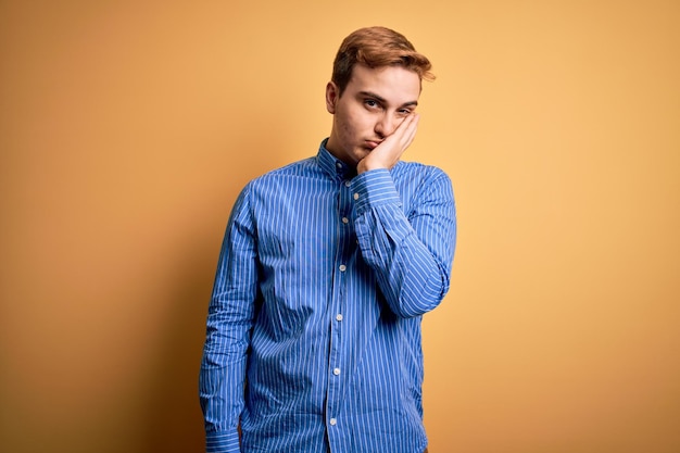 Foto grátis jovem ruivo bonito vestindo camisa listrada casual sobre fundo amarelo isolado pensando parecendo cansado e entediado com problemas de depressão com braços cruzados