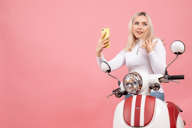 Jovem satisfeita em frente a uma motocicleta segurando o telefone