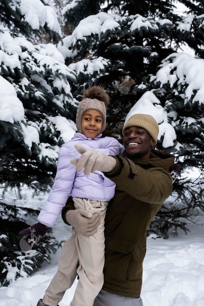 Jovem se divertindo com o pai em um dia de inverno nevado