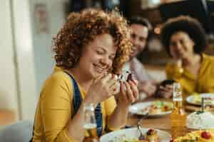 Foto grátis jovem se divertindo enquanto está sentado com seus amigos na mesa de jantar e comendo sobremesa