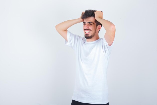 Jovem segurando a cabeça com as mãos na camiseta e parecendo fofo