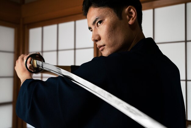 Jovem segurando a vista lateral da espada samurai