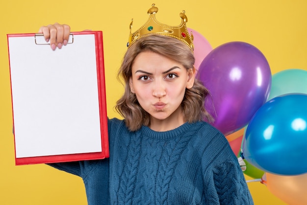 Jovem segurando balões coloridos e uma nota amarela