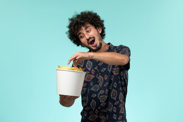 Jovem segurando batata cips e assistindo filme em uma parede azul cinema masculino cinema cinema.