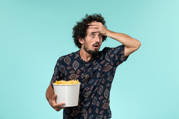 Jovem segurando batatas fritas em um cinema de parede azul claro