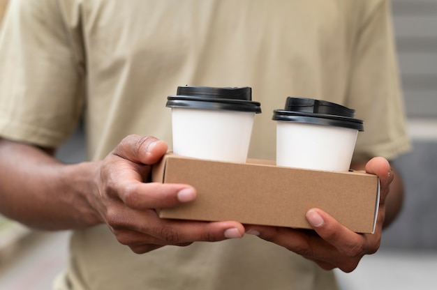 Foto grátis jovem segurando um café para viagem