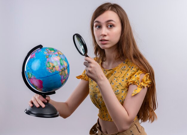 Foto grátis jovem segurando um globo e uma lupa, olhando para uma parede branca isolada