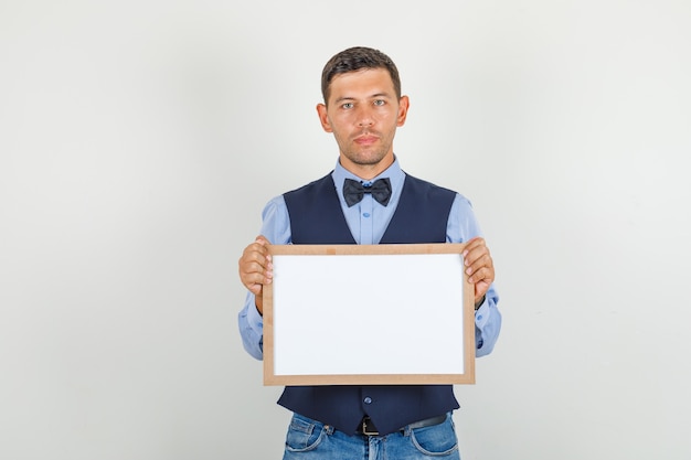 Jovem segurando um quadro branco de terno