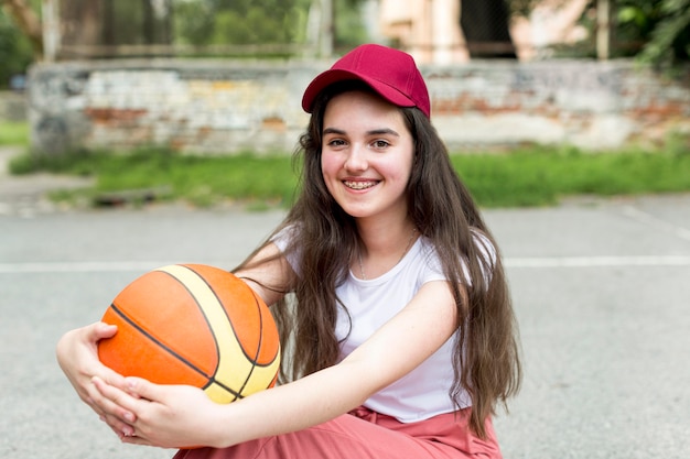 Jovem, segurando uma bola de basquete em sua amrs