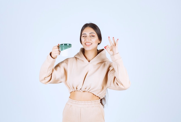 Jovem segurando uma caneca verde e mostrando sua satisfação