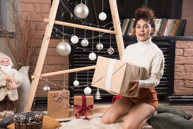 Jovem segurando uma grande caixa de presente de Natal