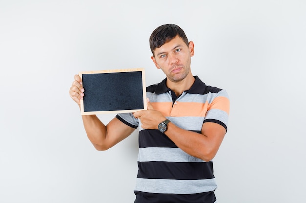 Jovem segurando uma lousa em uma camiseta e parecendo sensato