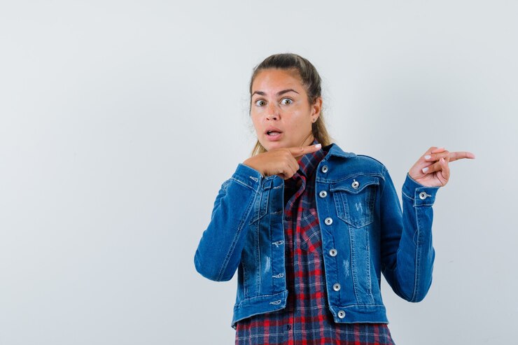 Foto grátis jovem senhora com camisa, jaqueta apontando para o lado e parecendo assustada, vista frontal.