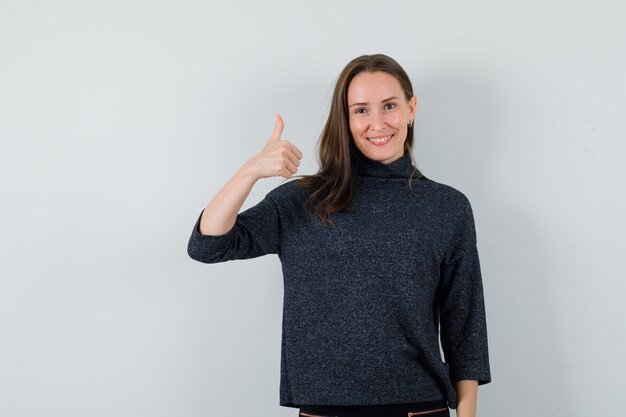 Jovem senhora com camisa, mostrando o polegar e parecendo alegre