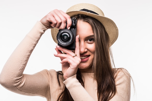Jovem senhora com camiseta brilhante e chapéu faz foto na retrocâmera isolada no branco