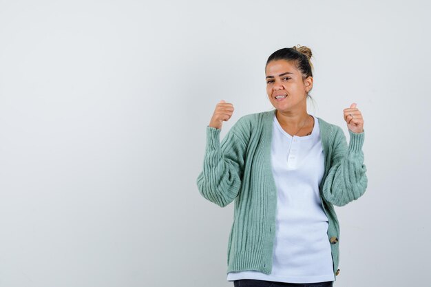 Jovem senhora com t-shirt, casaco a mostrar o gesto de vencedor e parecendo feliz