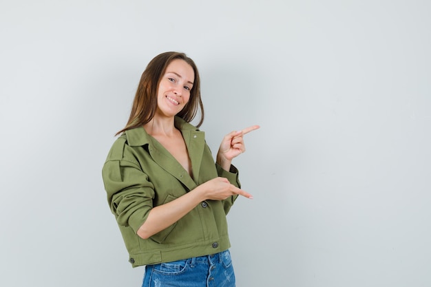 Foto grátis jovem senhora de bermuda apontando os dedos para cima e para baixo e parecendo alegre