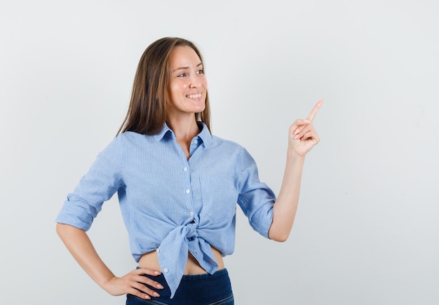 Jovem senhora de camisa azul, calça apontando para fora e parecendo alegre