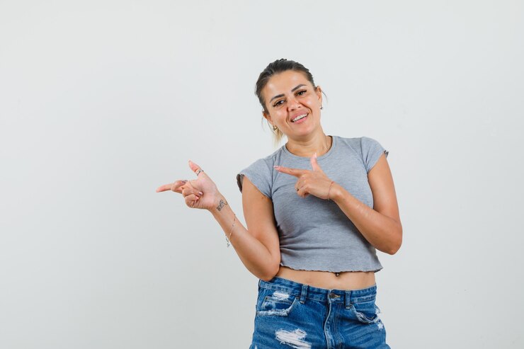 Foto grátis jovem senhora de camiseta, shorts apontando para o lado e parecendo otimista