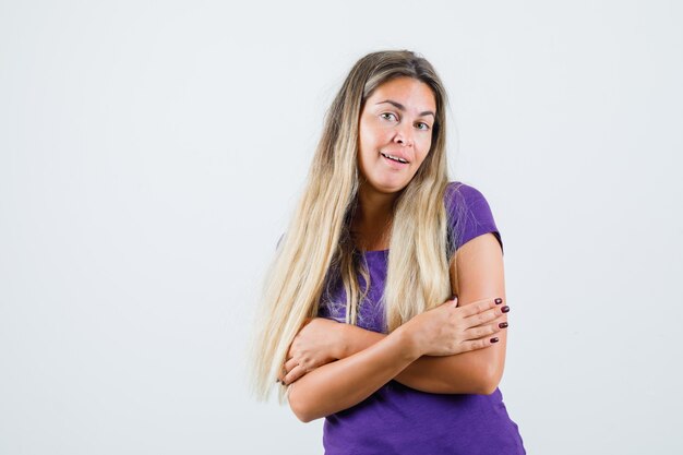 Jovem senhora de camiseta violeta, abraçando-se e bonita, vista frontal.