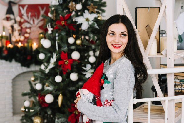 Jovem senhora sorridente perto de árvore de Natal