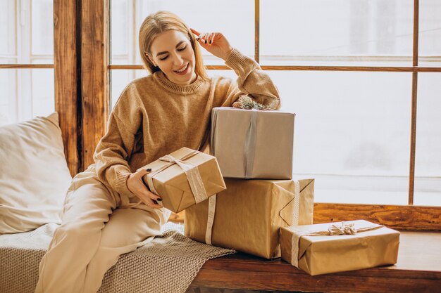 Jovem sentada perto da janela com presentes de Natal