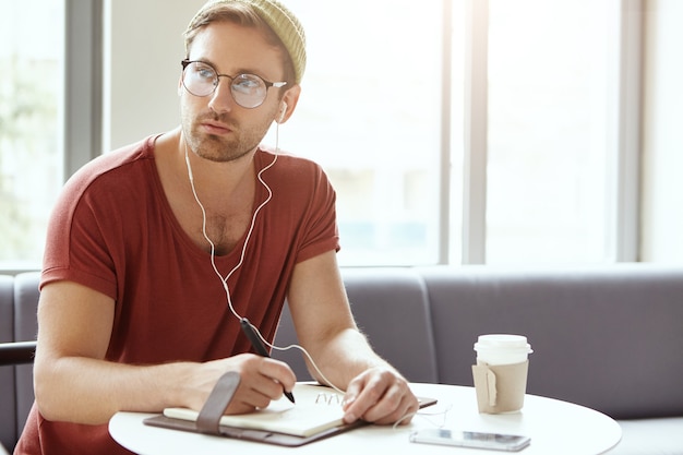 Jovem sentado em um café ouvindo música