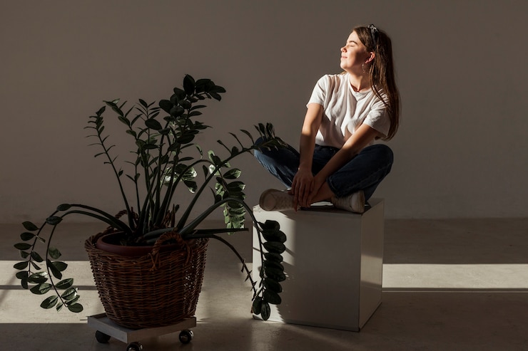 Foto grátis jovem sentado nas sombras e planta
