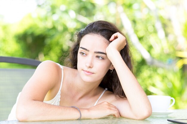 Jovem séria sentada à mesa ao ar livre