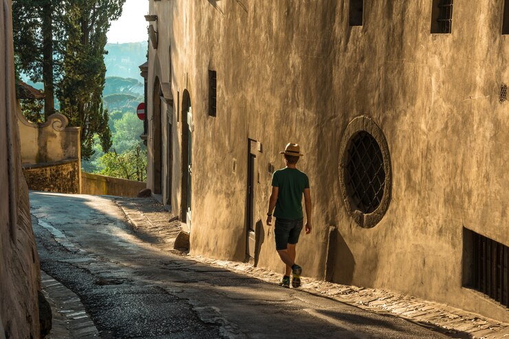 Foto grátis jovem solitário caminhando na rua ao lado de um antigo prédio de concreto