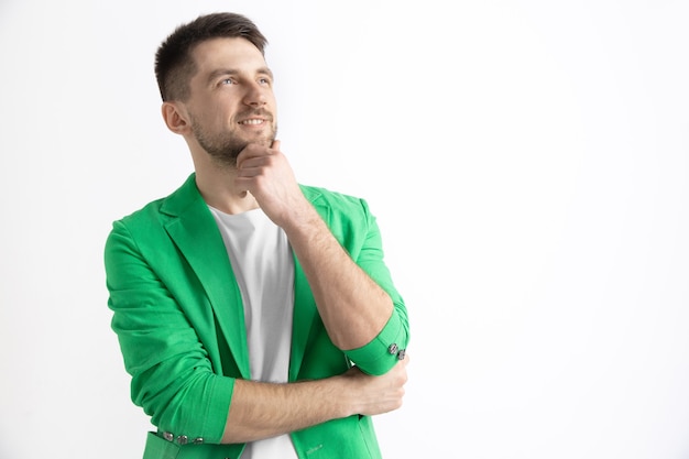 Foto grátis jovem sonhando homem sorridente está esperando por canções isoladas em cinza.