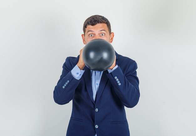 Jovem soprando um balão preto em um terno