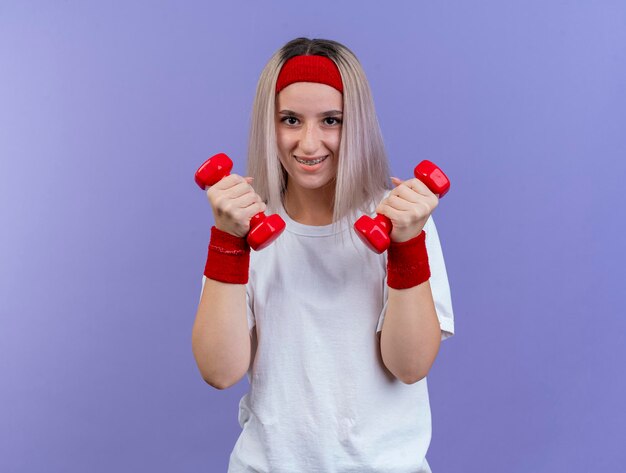 Jovem sorridente caucasiana desportiva com aparelho e faixa na cabeça